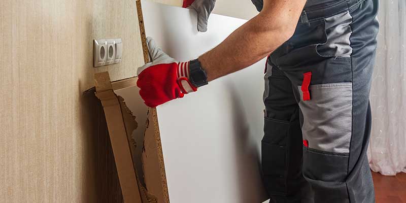 Man furniture assembler unpacks boxes boards